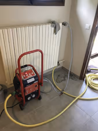 Machine de désembouage Virax raccordée par deux tuyaux à un radiateur
