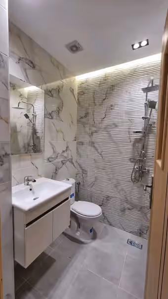 Salle d’eau refaite : carrelage marbré, colonne de douche, meuble vasque et WC